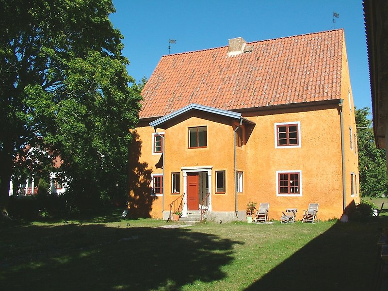 Ett trevånings orange hus med bruna dörrar och fönster.