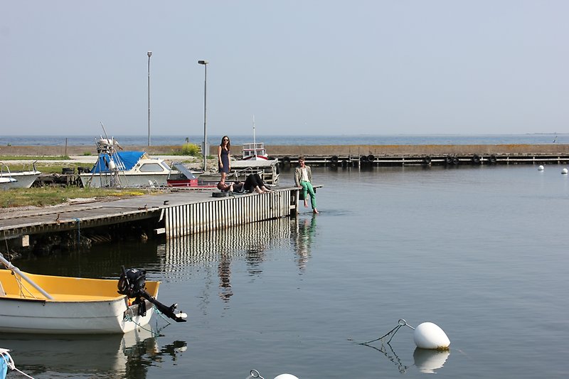 Flera små fiskebåtar är förtöjda vid bryggan i närheten av fiskebodarna.
