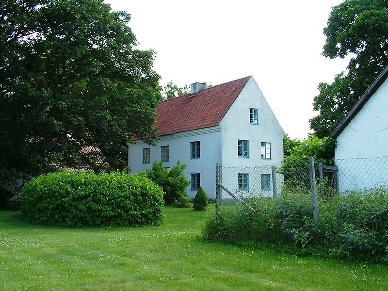 Ett vitt hus med rött tegeltak och nyklippt gräsmatta.